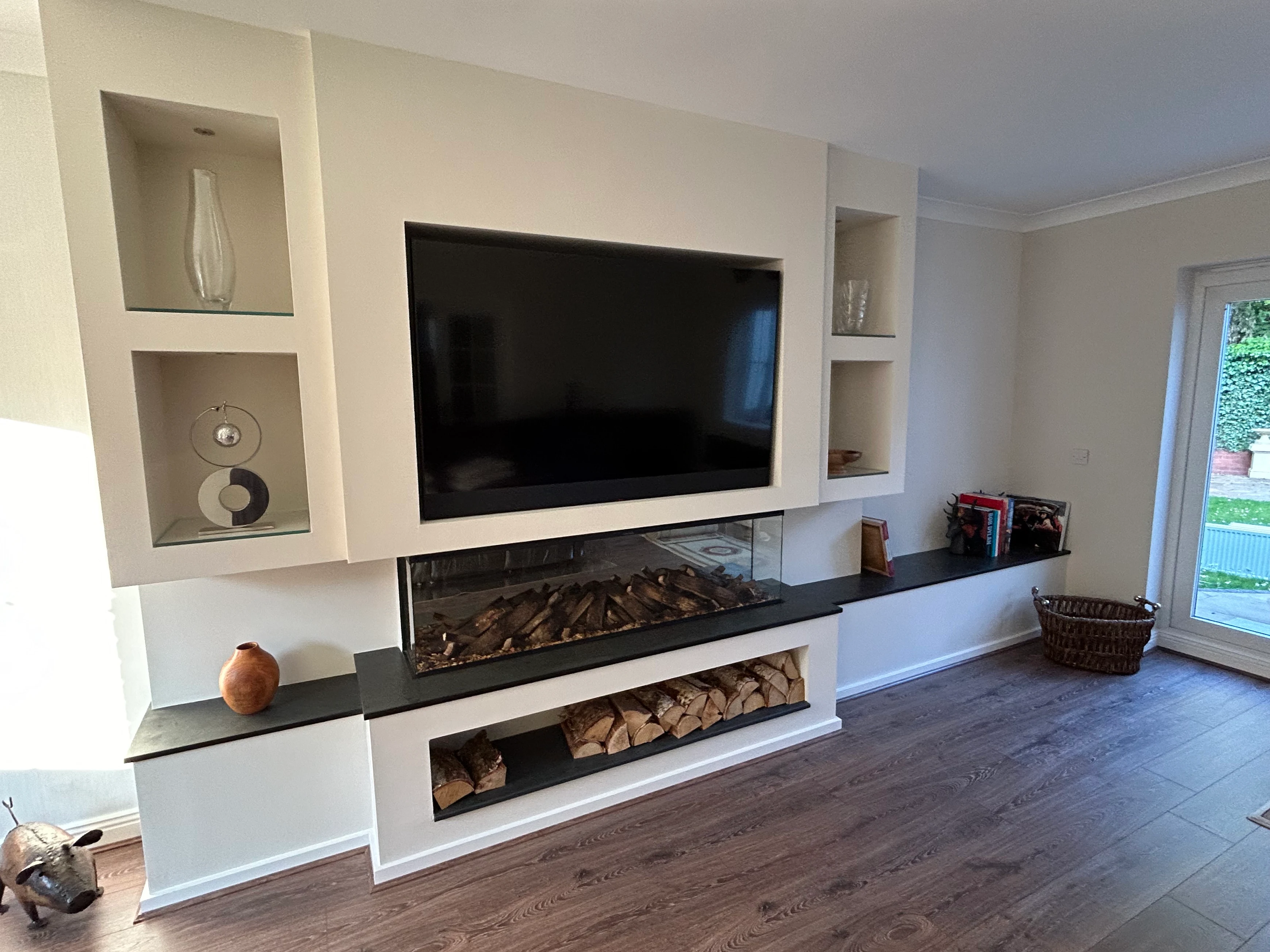 A bespoke media wall with an inset panoramic electric fire, recessed TV and display niches