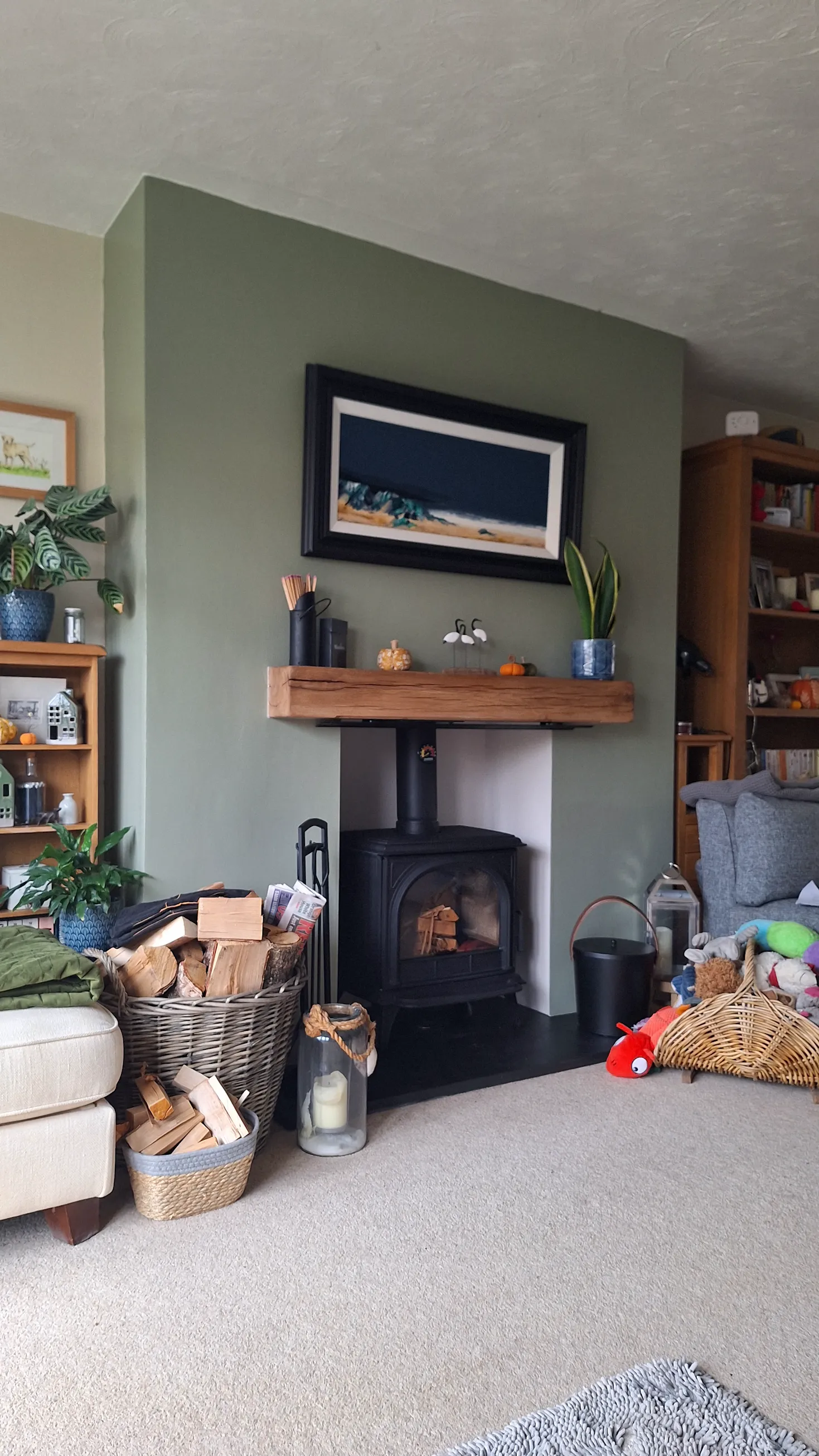 A black wood burning stove fitted in a white chamber with a solid oak beam mantel