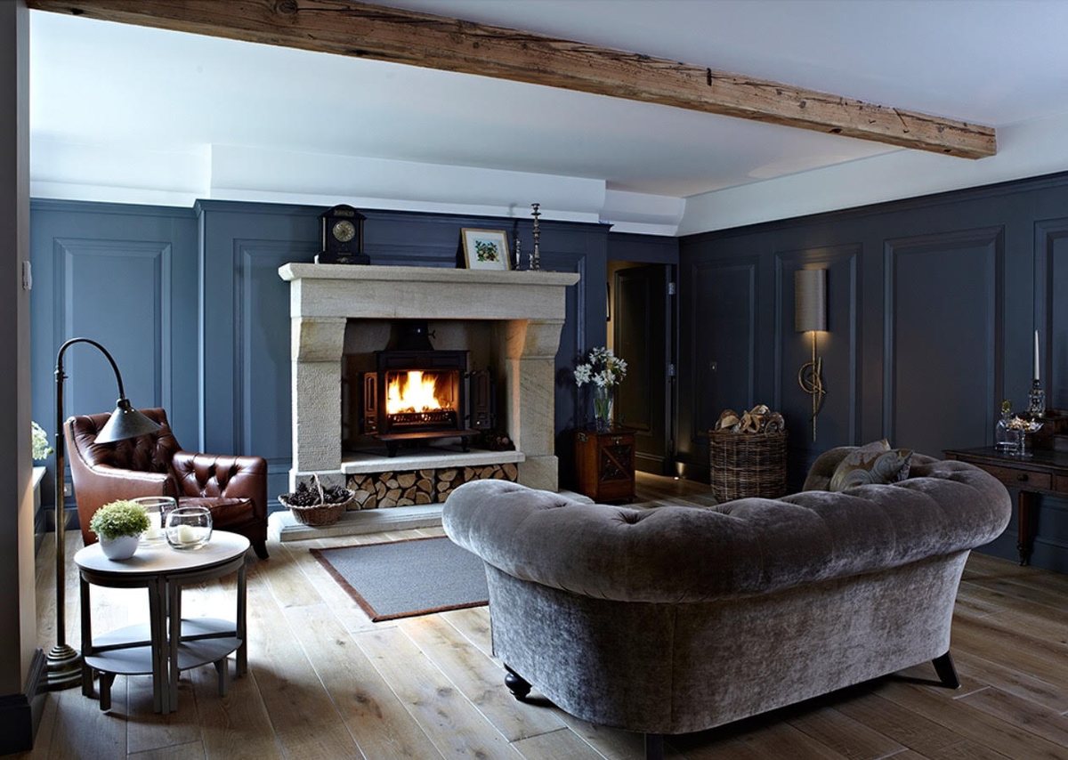 A natural stone fireplace with a wood burning stove and log store in a panelled living room